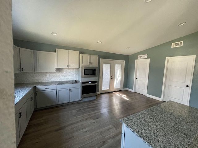 323 E Grand St, Whitewright, TX 75491 - kitchen featuring appliances with stainless steel finishes, dark wood-style flooring, lofted ceiling, decorative backsplash, and baseboards