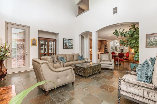 2605 Cherry Sage Dr, Flower Mound, TX 75022 - living area with arched walkways, a high ceiling, and stone tile flooring
