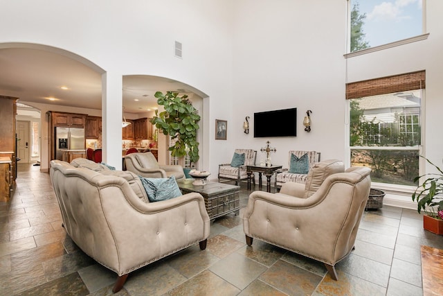2605 Cherry Sage Dr, Flower Mound, TX 75022 - living area featuring arched walkways, a towering ceiling, healthy amount of natural light, stone tile flooring, and recessed lighting