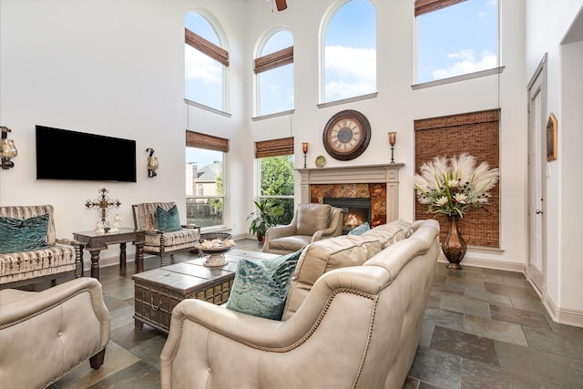 2605 Cherry Sage Dr, Flower Mound, TX 75022 - living area with a towering ceiling, baseboards, a fireplace, dark stone finish flooring, and a ceiling fan