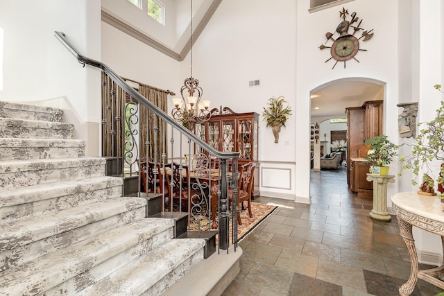 2605 Cherry Sage Dr, Flower Mound, TX 75022 - stairs featuring a high ceiling, stone tile flooring, a chandelier, arched walkways, and baseboards