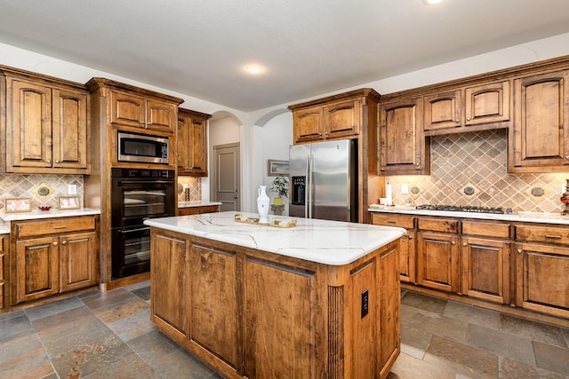 2605 Cherry Sage Dr, Flower Mound, TX 75022 - kitchen with stainless steel appliances, arched walkways, a kitchen island, stone tile flooring, and backsplash