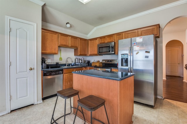 223 Troy Ln, Red Oak, TX 75154 - kitchen featuring stainless steel appliances, arched walkways, brown cabinetry, dark countertops, and a center island