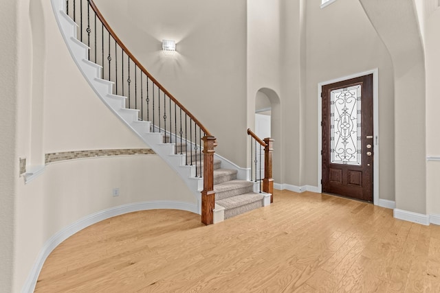 7048 Fullerton Cir, Frisco, TX 75035 - entrance foyer featuring wood finished floors, a high ceiling, stairway, baseboards, and arched walkways
