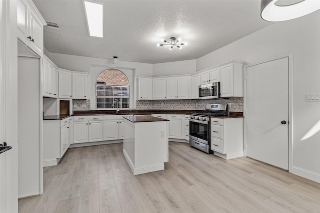 7129 Don Gomez Ln, Garland, TX 75043 - kitchen with appliances with stainless steel finishes, a textured ceiling, dark countertops, light wood-style floors, and tasteful backsplash