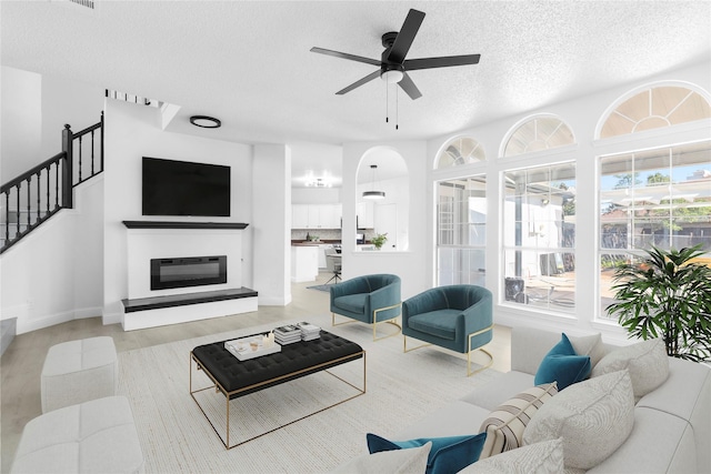 7129 Don Gomez Ln, Garland, TX 75043 - living room with a textured ceiling, ceiling fan, wood finished floors, stairs, and a glass covered fireplace