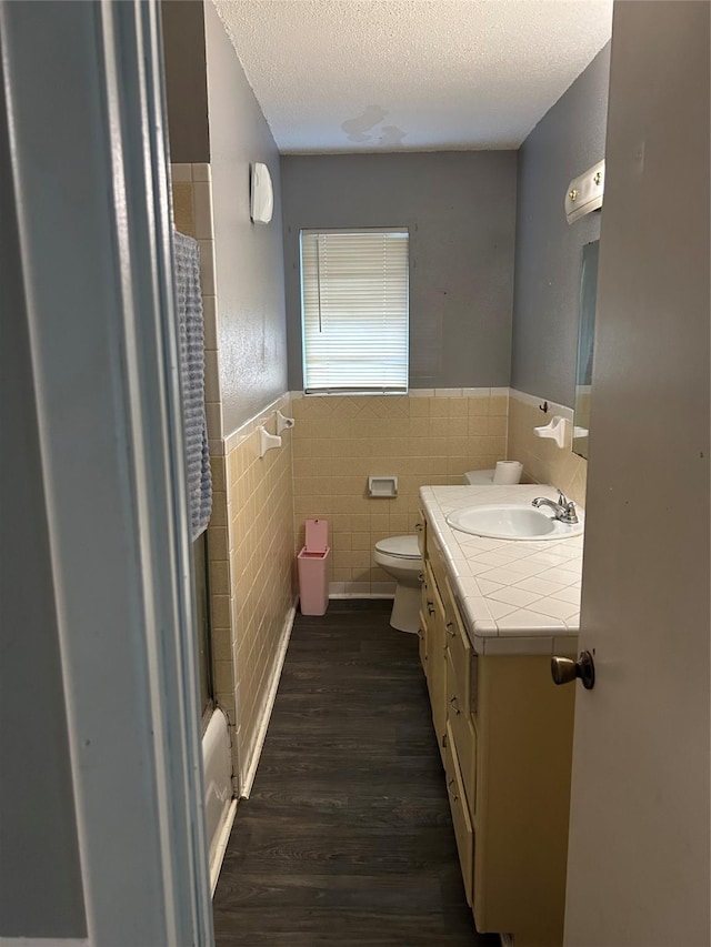 1024 W Chestnut St, Denison, TX 75020 - full bathroom with a shower with shower curtain, wainscoting, tile walls, wood finished floors, and toilet