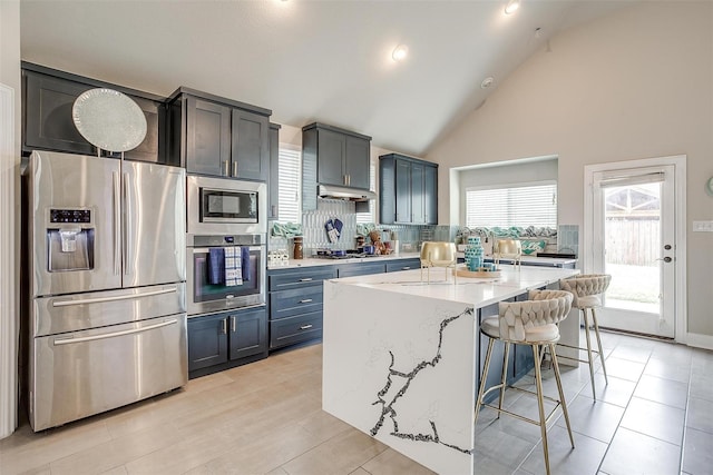 3015 Ruby Dr, Wylie, TX 75098 - kitchen featuring stainless steel appliances, light stone countertops, a center island, a breakfast bar area, and under cabinet range hood