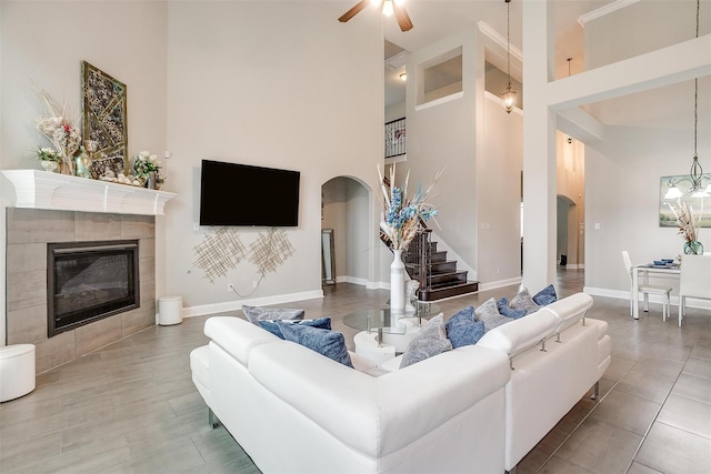 3015 Ruby Dr, Wylie, TX 75098 - living room with arched walkways, a towering ceiling, a tiled fireplace, baseboards, and ceiling fan
