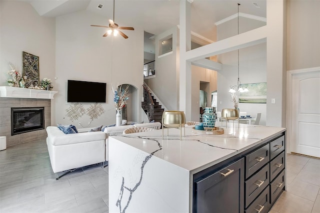 3015 Ruby Dr, Wylie, TX 75098 - kitchen featuring high vaulted ceiling, ceiling fan, a tiled fireplace, light stone counters, and light tile patterned floors