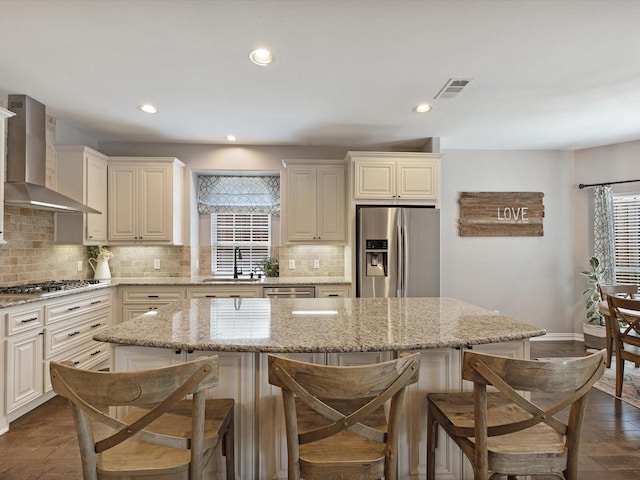 1505 Taylor Ln, Mckinney, TX 75071 - kitchen with appliances with stainless steel finishes, wall chimney exhaust hood, a sink, a breakfast bar, and tasteful backsplash