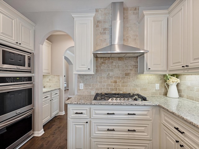 1505 Taylor Ln, Mckinney, TX 75071 - kitchen featuring wall chimney range hood, stainless steel appliances, tasteful backsplash, white cabinets, and dark wood finished floors