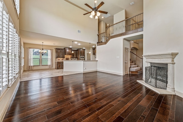 10601 San Simeon Ln, Fort Worth, TX 76179 - unfurnished living room with ceiling fan, wood finished floors, a fireplace with raised hearth, a chandelier, and a towering ceiling