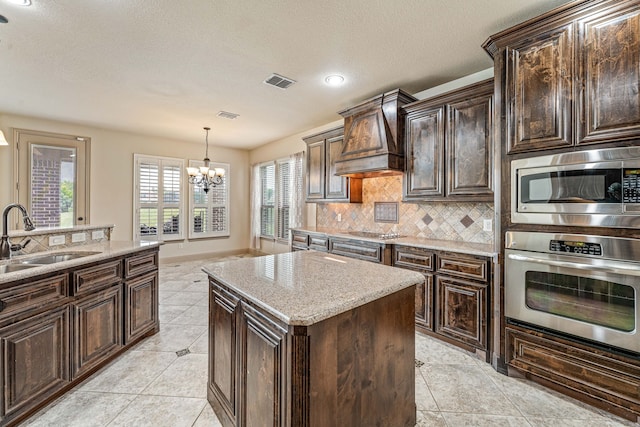 10601 San Simeon Ln, Fort Worth, TX 76179 - kitchen featuring stainless steel appliances, a sink, a chandelier, backsplash, and a center island