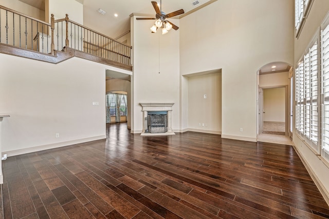 10601 San Simeon Ln, Fort Worth, TX 76179 - unfurnished living room with arched walkways, ceiling fan, wood-type flooring, a towering ceiling, and a fireplace with raised hearth