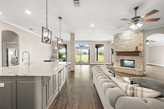 1009 Maida Vale, Haslet, TX 76052 - living area with ceiling fan, dark wood-style flooring, arched walkways, crown molding, and a fireplace