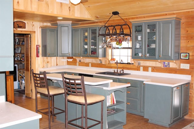 1147 Rs County Road 3503, Emory, TX 75440 - kitchen featuring wood walls, gray cabinets, a sink, a kitchen island, and a kitchen breakfast bar