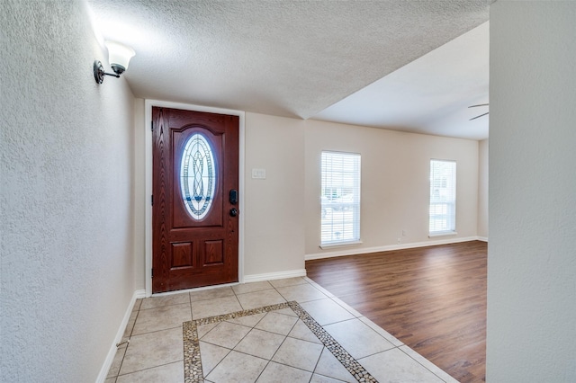 5072 Stanley Dr, The Colony, TX 75056 - foyer with a textured wall, baseboards, a textured ceiling, tile patterned floors, and inlaid floor details