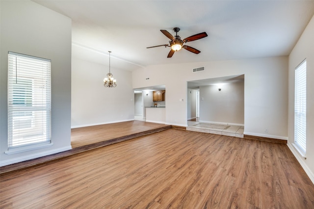 5072 Stanley Dr, The Colony, TX 75056 - unfurnished living room with lofted ceiling, a ceiling fan, a chandelier, light wood-type flooring, and baseboards