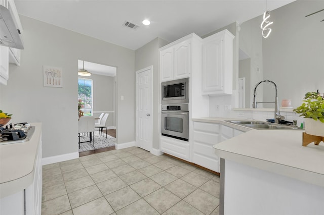 3925 Wisteria Ln, Haltom City, TX 76137 - kitchen featuring stainless steel appliances, white cabinetry, light countertops, pendant lighting, and light tile patterned floors