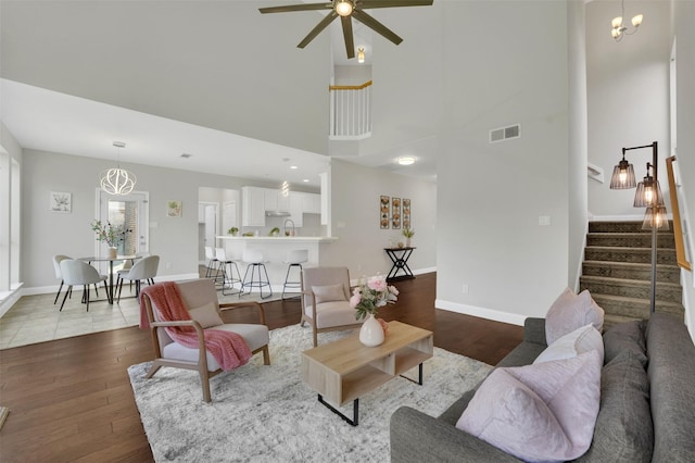 3925 Wisteria Ln, Haltom City, TX 76137 - living area featuring wood finished floors, ceiling fan, stairway, a high ceiling, and a chandelier