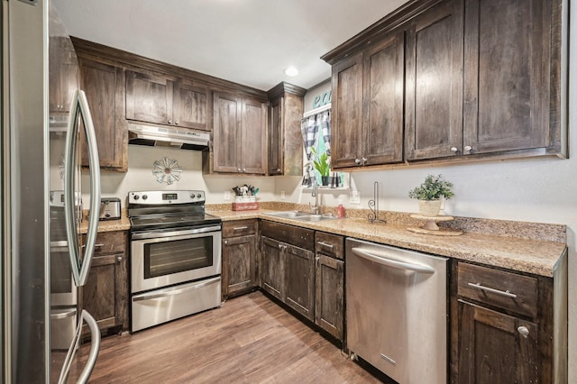104 S Cedar St, Leonard, TX 75452 - kitchen with appliances with stainless steel finishes, under cabinet range hood, dark brown cabinetry, light wood finished floors, and a sink