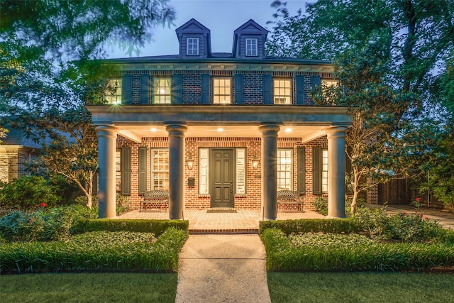 colonial inspired home with covered porch and brick siding