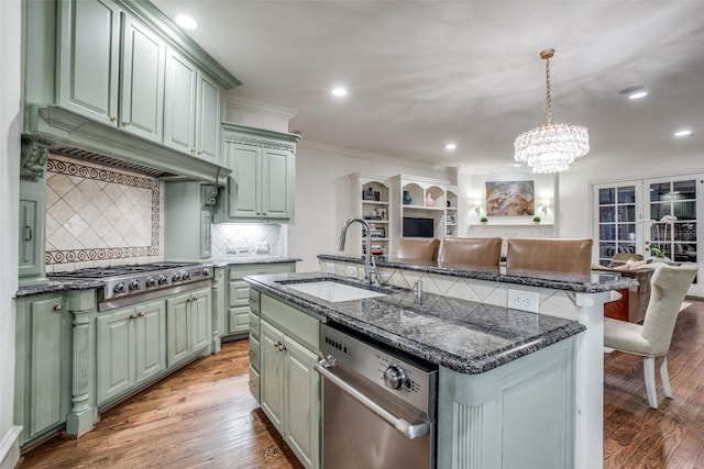 kitchen with a sink, stainless steel appliances, ornamental molding, tasteful backsplash, and green cabinetry