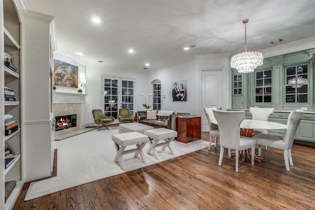 living room featuring ornamental molding, a premium fireplace, wood finished floors, recessed lighting, and a chandelier