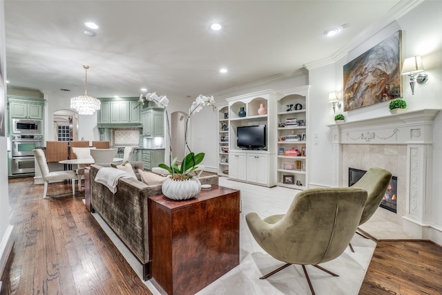 living area featuring wood finished floors, recessed lighting, a high end fireplace, built in features, and ornamental molding