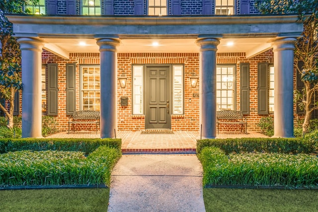 view of exterior entry with covered porch and brick siding