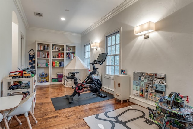 workout room with wood finished floors, ornamental molding, recessed lighting, and baseboards