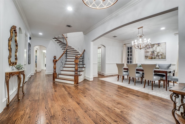 dining area featuring arched walkways, stairs, wood finished floors, ornamental molding, and recessed lighting