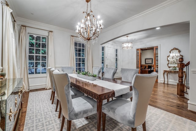dining room featuring a chandelier, wood finished floors, crown molding, arched walkways, and baseboard heating