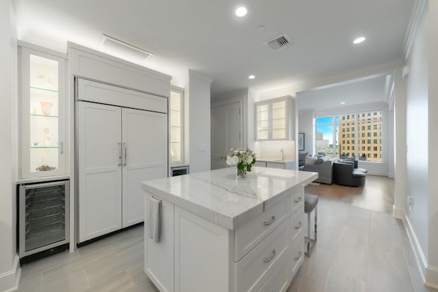 2525 N Pearl St Unit 1203, Dallas, TX 75201 - kitchen with beverage cooler, a center island, ornamental molding, light stone counters, and glass insert cabinets