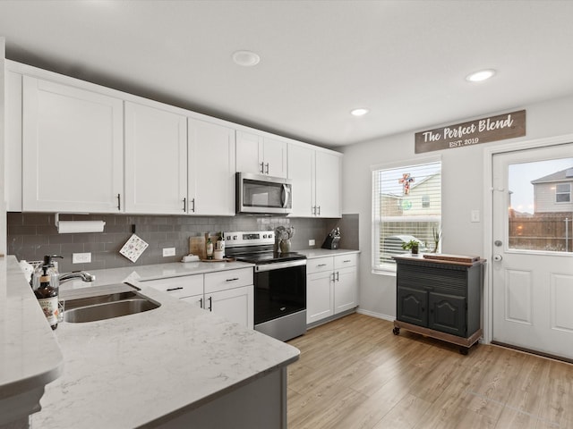 1359 Panorama Dr, Forney, TX 75126 - kitchen with stainless steel appliances, a sink, white cabinetry, decorative backsplash, and light wood-style flooring