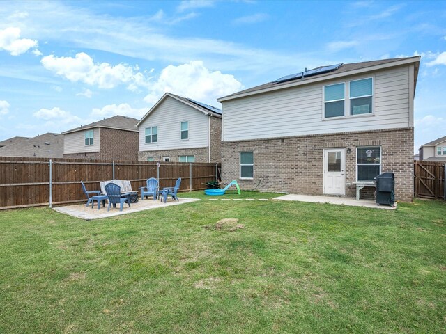 1359 Panorama Dr, Forney, TX 75126 - back of property with a patio, brick siding, roof mounted solar panels, and an outdoor fire pit