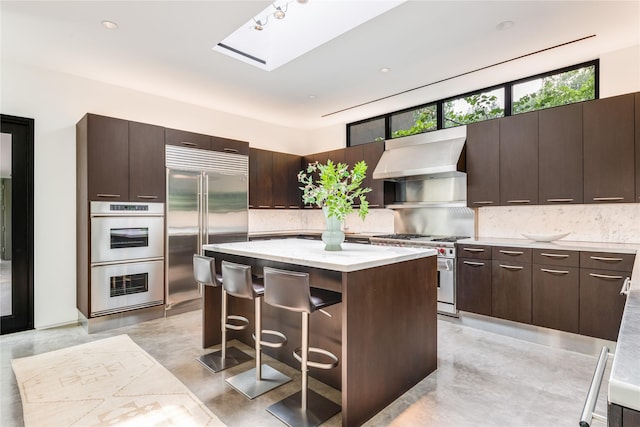 kitchen with high end appliances, range hood, a center island, and tasteful backsplash