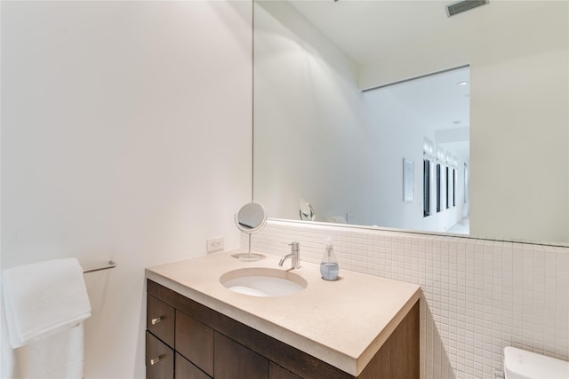 bathroom with vanity, tile walls, and toilet