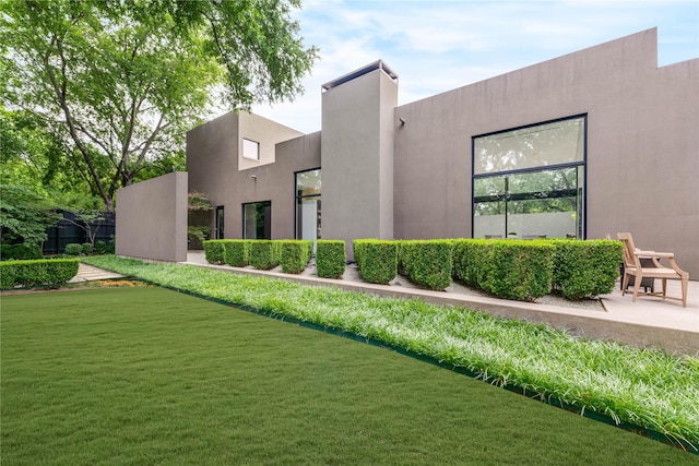 rear view of property with a yard and stucco siding