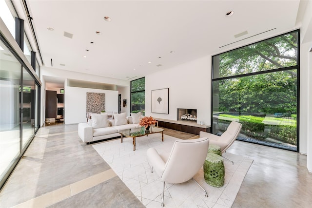 living room featuring expansive windows, a fireplace with raised hearth, and recessed lighting