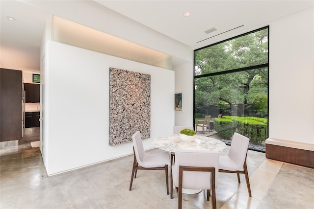 dining space with a wall of windows, concrete floors, and recessed lighting