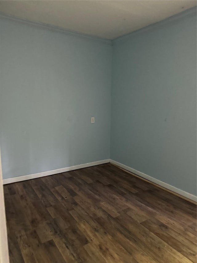 unfurnished room with crown molding, dark wood-style flooring, and baseboards