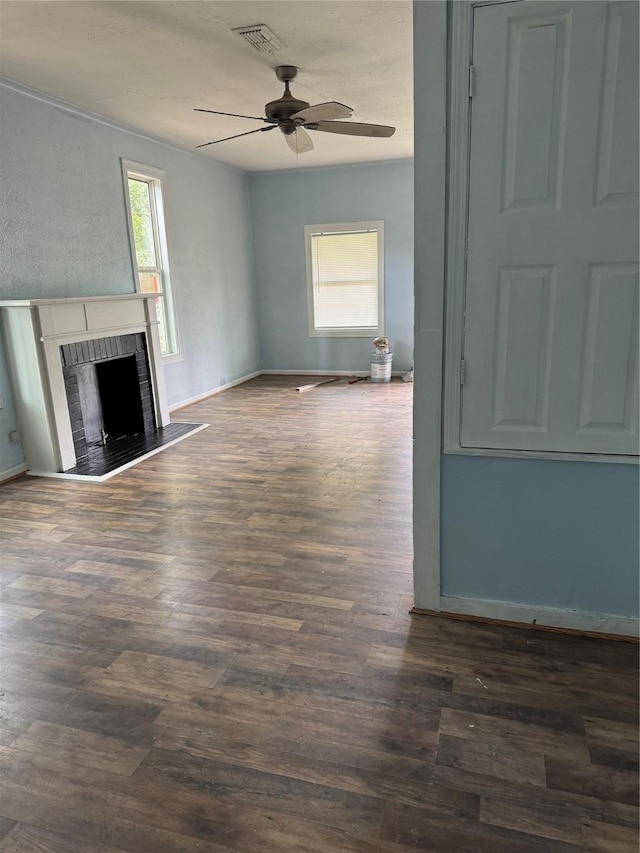 unfurnished living room with ceiling fan, a fireplace, dark wood finished floors, and baseboards