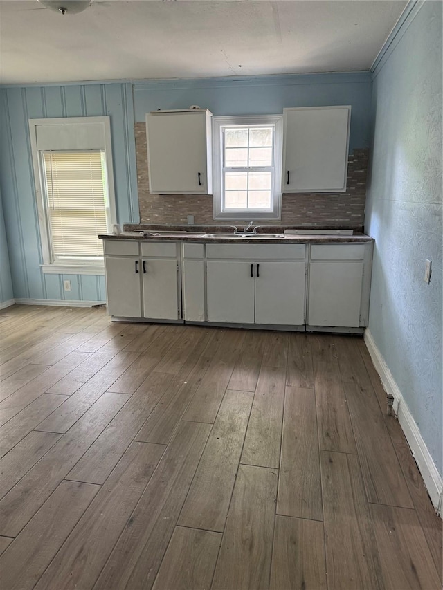 kitchen featuring dark countertops, wood finished floors, a sink, and white cabinetry