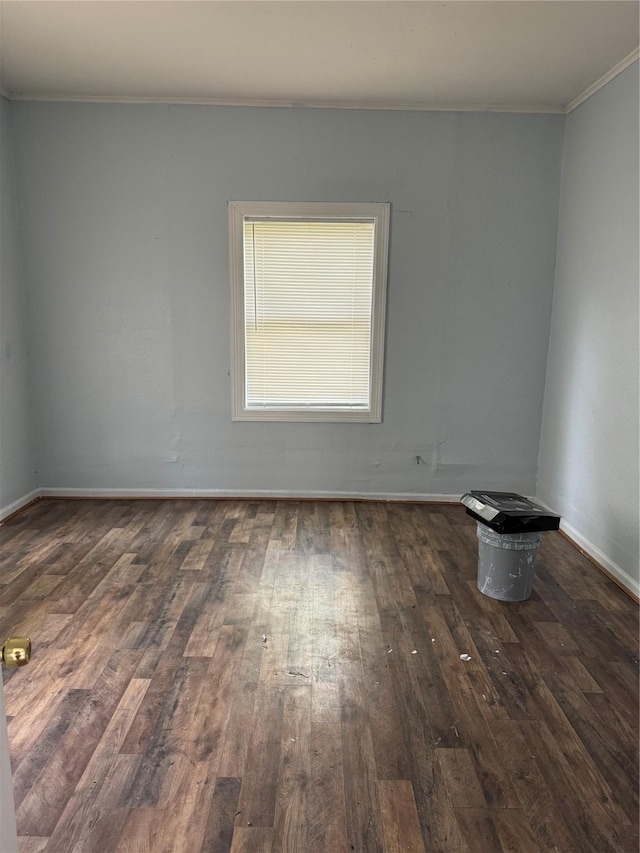 empty room with crown molding, hardwood / wood-style flooring, and baseboards