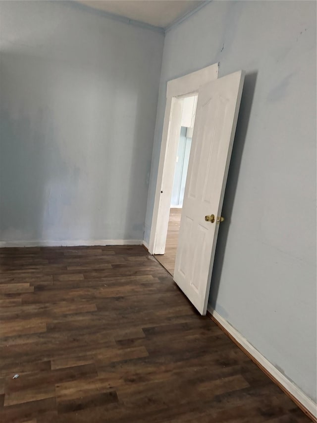 empty room featuring dark wood-style floors and baseboards