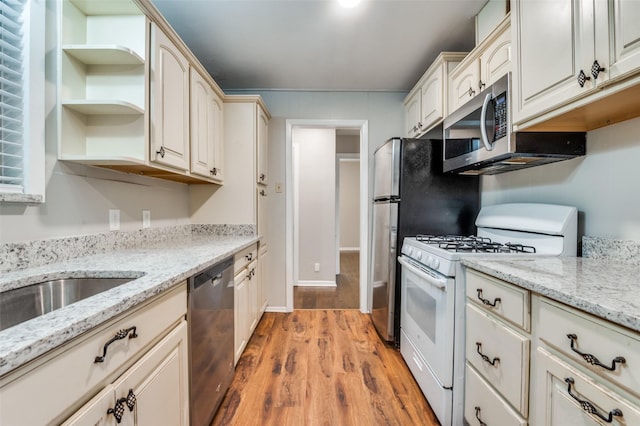 2018 Shawnee St, Denton, TX 76209 - kitchen featuring appliances with stainless steel finishes, open shelves, light wood finished floors, and light stone countertops