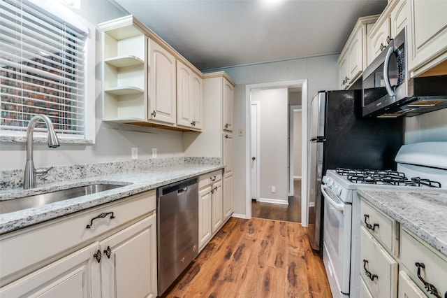 2018 Shawnee St, Denton, TX 76209 - kitchen featuring appliances with stainless steel finishes, wood finished floors, a sink, open shelves, and light stone counters