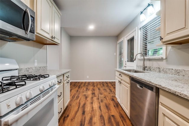 2018 Shawnee St, Denton, TX 76209 - kitchen with stainless steel appliances, a sink, dark wood-style floors, baseboards, and light stone countertops